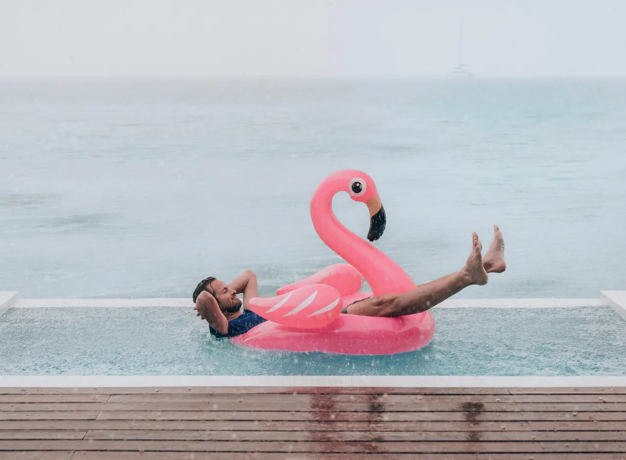 man relaxing in pool flamingo in the rain 